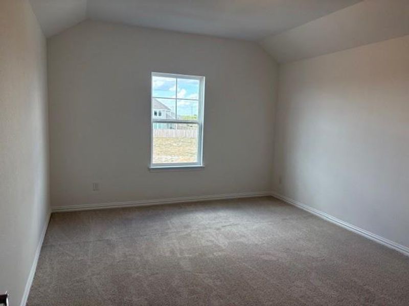 Spare room with vaulted ceiling and light colored carpet Spare room with vaulted ceiling and light colored carpet