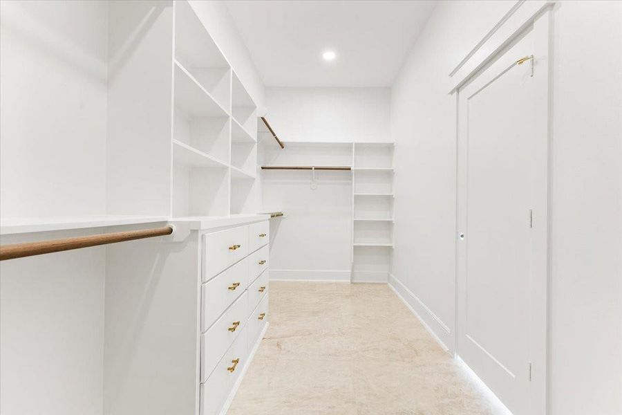 Expansive walk-in primary closet with custom built-in shelving and storage. Expansive walk-in primary closet with custom built-in shelving and storage.
