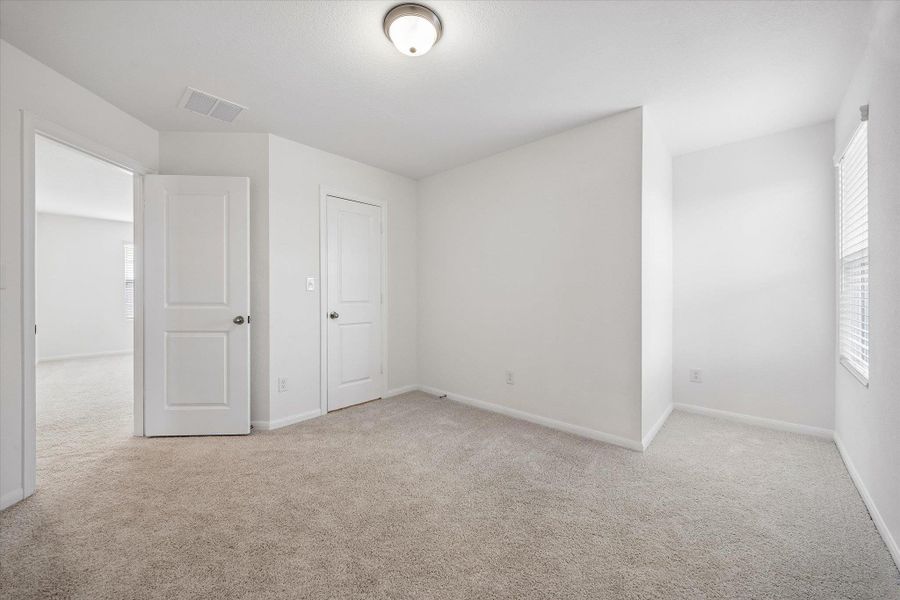 Unfurnished bedroom with multiple windows and light colored carpet
