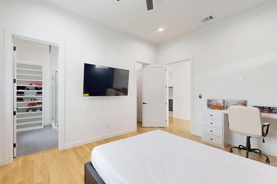 Bedroom with light wood-style floors, a walk in closet, an office area, ceiling fan, and recessed lighting Bedroom with light wood-style floors, a walk in closet, an office area, ceiling fan, and recessed lighting