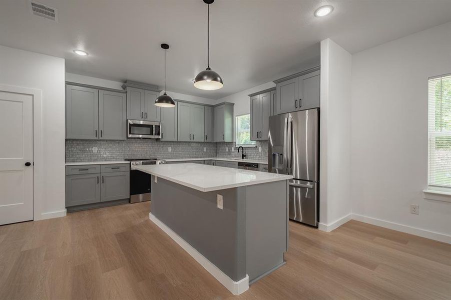 Kitchen featuring stainless steel appliances, gray cabinetry, light wood-style floors, tasteful backsplash, and recessed lighting Kitchen featuring stainless steel appliances, gray cabinetry, light wood-style floors, tasteful backsplash, and recessed lighting
