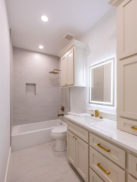 Modern bathroom with elegant fixtures, a spacious vanity with dual sinks, and a backlit mirror. It features a bathtub with a shower, soft lighting, and ample storage in white cabinetry.