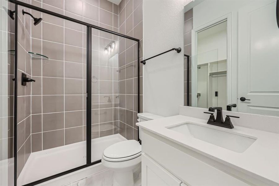 Bathroom with vanity, toilet, and a shower with shower door