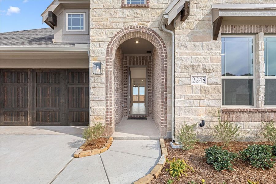 Home entrance with brick arched doorway, stone exterior, and wood garage door at address 2248 Home entrance with brick arched doorway, stone exterior, and wood garage door at address 2248