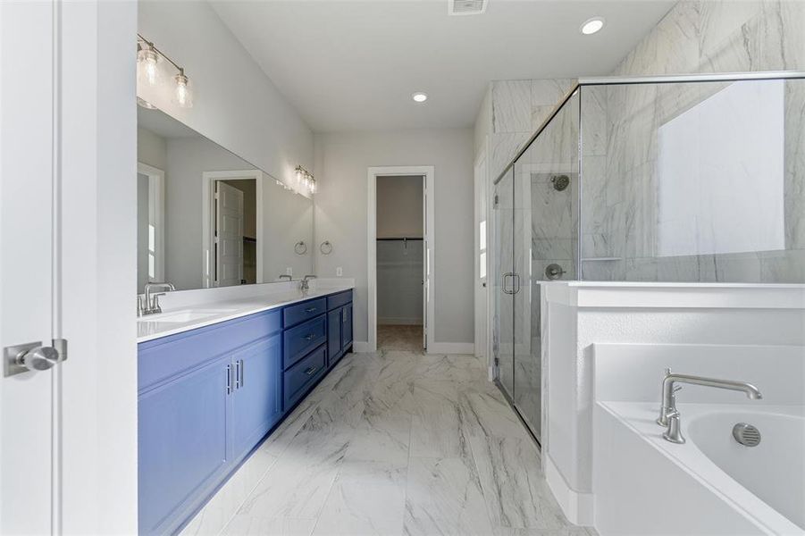 Bathroom featuring double vanity, a bath, a walk in closet, recessed lighting, and a marble finish shower