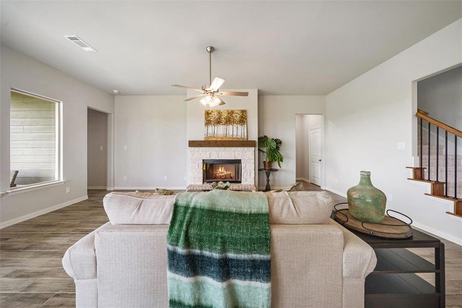 Living room featuring wood finished floors, stairs, a fireplace, and a ceiling fan Living room featuring wood finished floors, stairs, a fireplace, and a ceiling fan