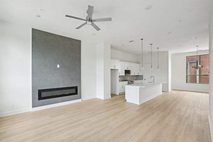 Unfurnished living room featuring baseboards, light wood-style floors, a fireplace, and a ceiling fan