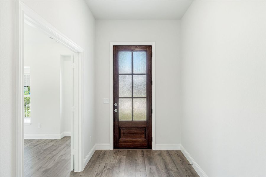 Entryway with dark wood door featuring frosted glass panels and gray hardwood floors Entryway with dark wood door featuring frosted glass panels and gray hardwood floors