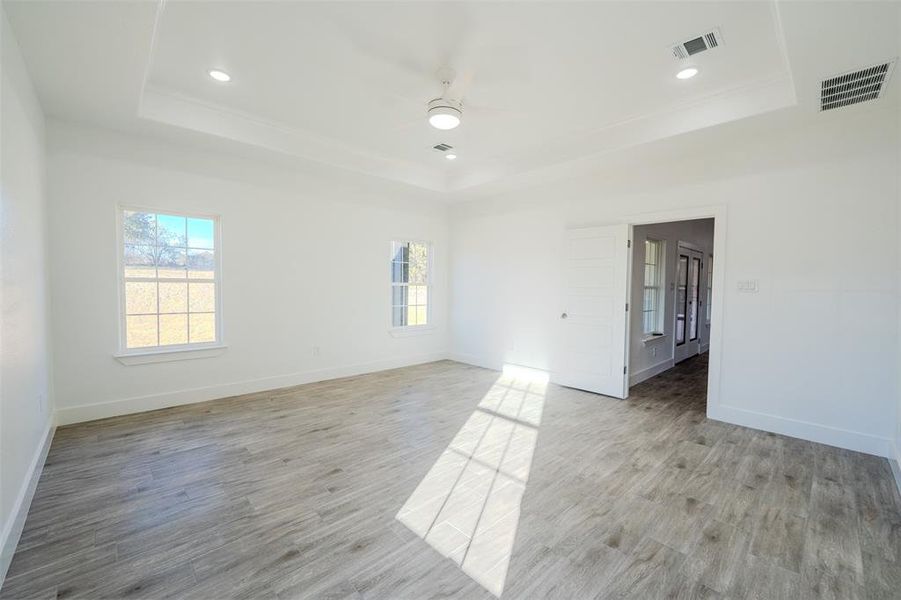 Unfurnished room featuring a tray ceiling, plenty of natural light, light wood-style floors, and recessed lighting Unfurnished room featuring a tray ceiling, plenty of natural light, light wood-style floors, and recessed lighting