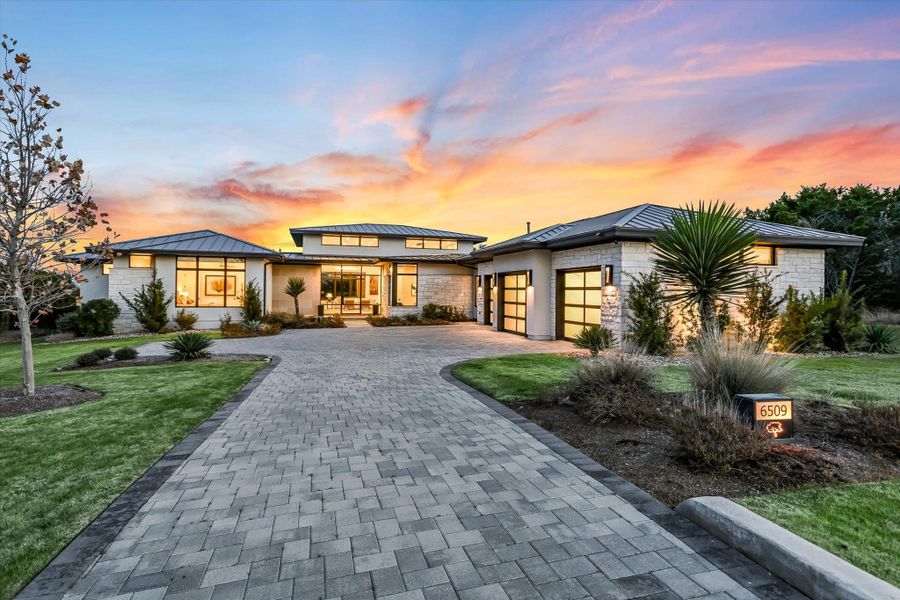 Prairie-style home featuring a standing seam roof, decorative driveway, a front lawn, roof mounted solar panels, and a garage Prairie-style home featuring a standing seam roof, decorative driveway, a front lawn, roof mounted solar panels, and a garage