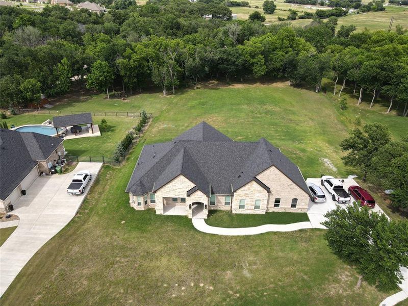 Expansive property featuring a stone and brick facade residence with a dark shingle roof Expansive property featuring a stone and brick facade residence with a dark shingle roof