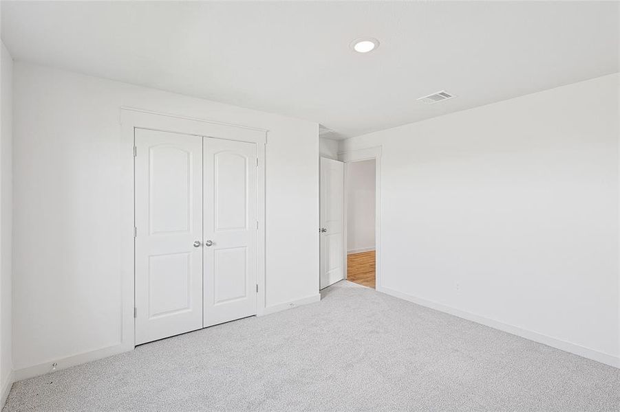 Unfurnished bedroom featuring a closet and light colored carpet