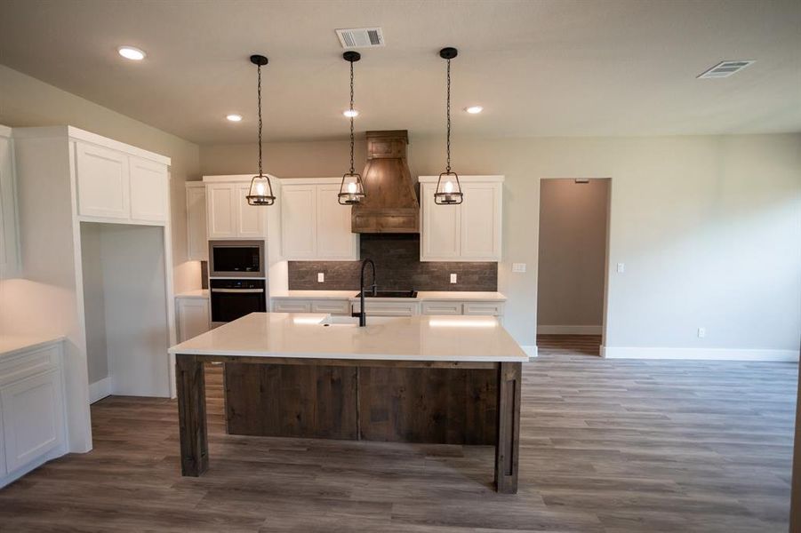 Kitchen featuring white cabinets, hanging light fixtures, black appliances, a breakfast bar area, and recessed lighting Kitchen featuring white cabinets, hanging light fixtures, black appliances, a breakfast bar area, and recessed lighting