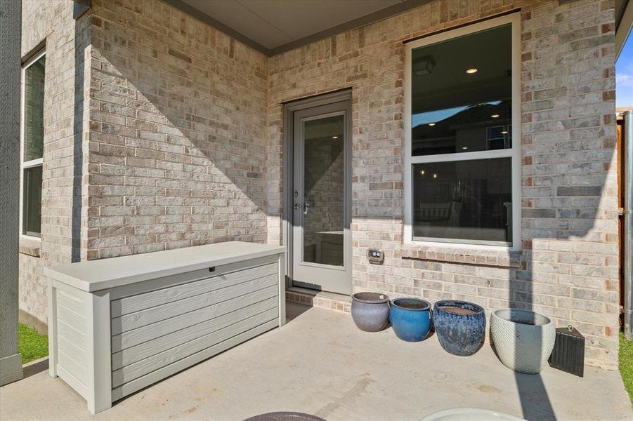 Covered patio featuring a concrete slab and light-toned brick exterior