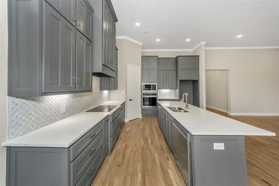 Kitchen with gray cabinets, sink, and appliances with stainless steel finishes