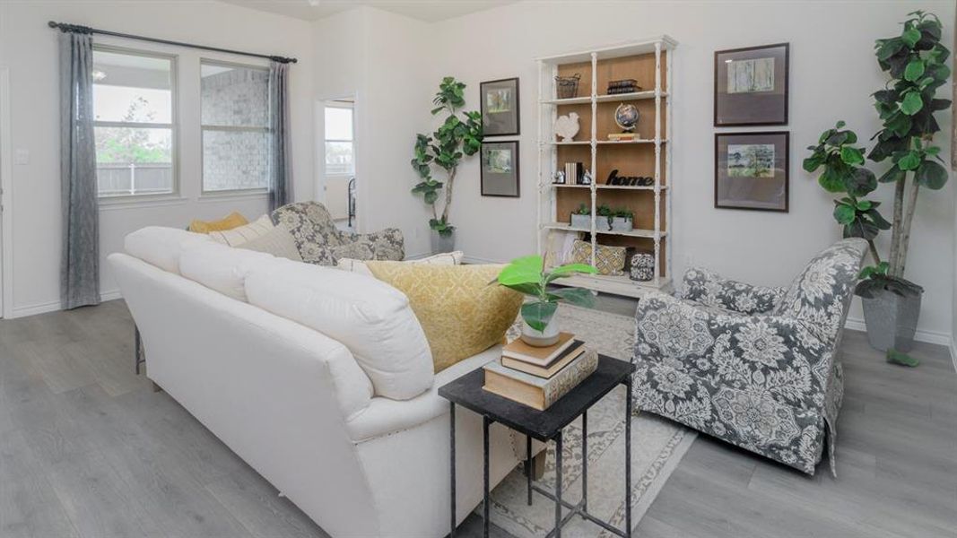 Spacious living area featuring light gray wood-finish flooring and ample natural light through multiple windows