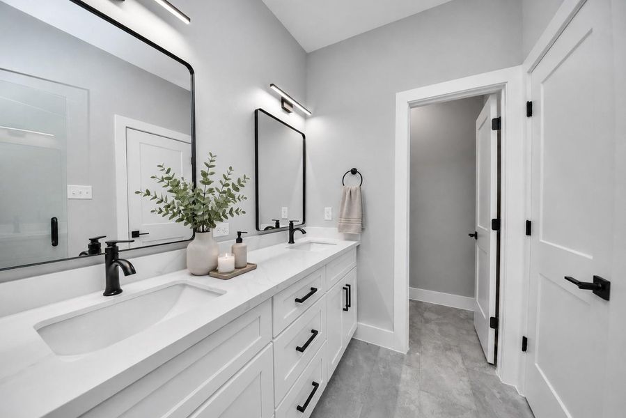Modern bathroom featuring dual vanities, sleek black fixtures, quartz countertops, & clean contemporary finishes throughout.