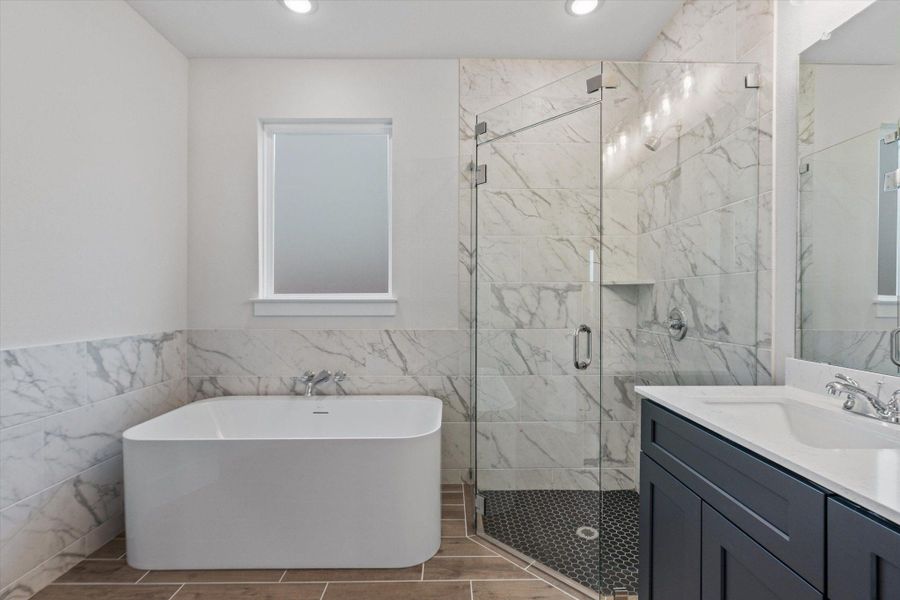 Indulge in a tranquil bathing experience within this well-appointed space, featuring a standalone tub and elegant glass-enclosed shower.