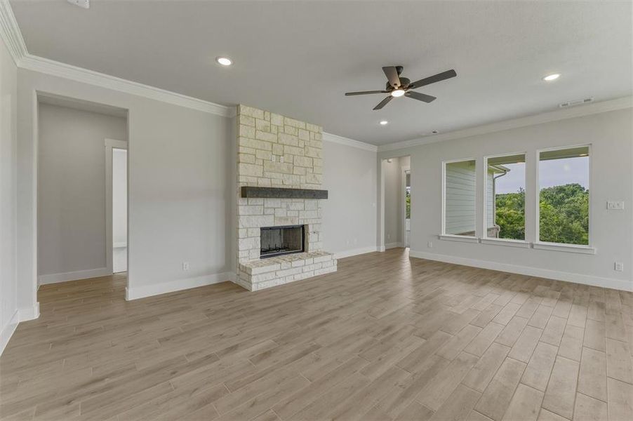 Spacious living area featuring a stacked stone fireplace with a dark wood mantel, recessed lighting, and a ceiling fan Spacious living area featuring a stacked stone fireplace with a dark wood mantel, recessed lighting, and a ceiling fan