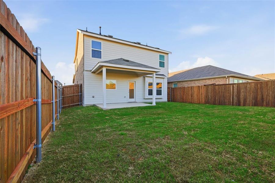 Expansive backyard featuring a manicured lawn, a covered patio, a full privacy fence, and a two-story exterior with light-colored siding Expansive backyard featuring a manicured lawn, a covered patio, a full privacy fence, and a two-story exterior with light-colored siding