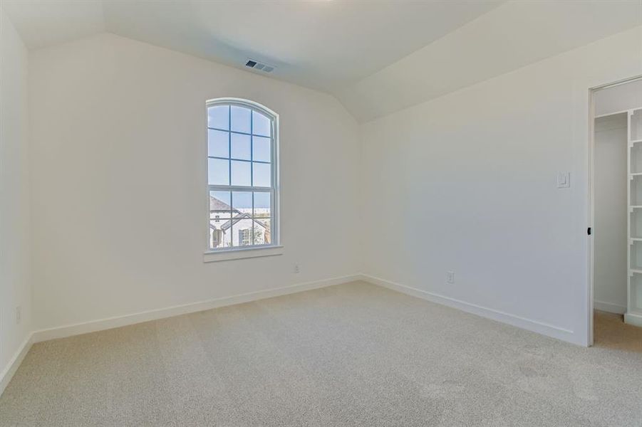 Empty room with lofted ceiling and light carpet