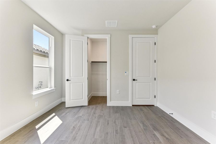Unfurnished bedroom featuring a spacious closet and light wood-style floors Unfurnished bedroom featuring a spacious closet and light wood-style floors