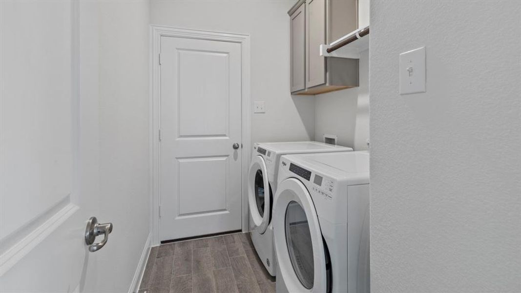 Washroom featuring wood finish floors, cabinet space, and separate washer and dryer