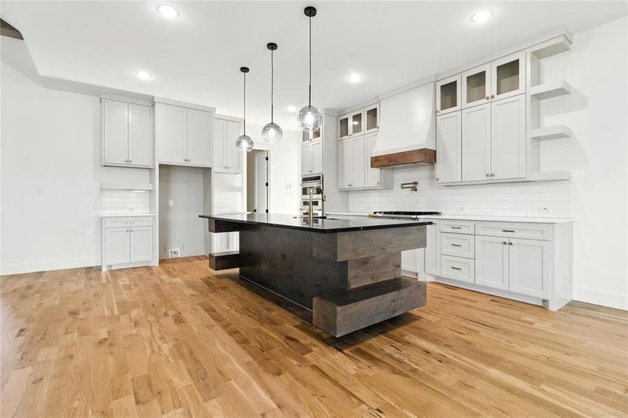 Kitchen featuring open shelves, light wood-style floors, tasteful backsplash, custom range hood, and recessed lighting Kitchen featuring open shelves, light wood-style floors, tasteful backsplash, custom range hood, and recessed lighting