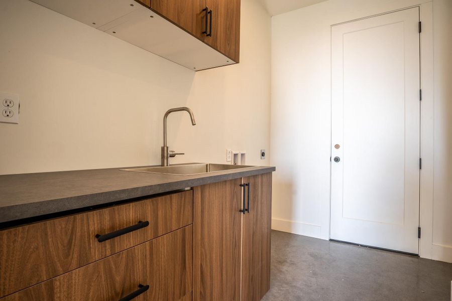 Bar area with brown cabinetry, concrete flooring, dark countertops, and modern cabinets