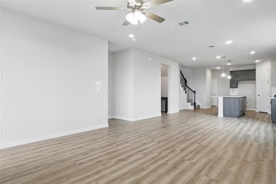 Unfurnished living room featuring recessed lighting, light wood finished floors, ceiling fan, and stairs Unfurnished living room featuring recessed lighting, light wood finished floors, ceiling fan, and stairs
