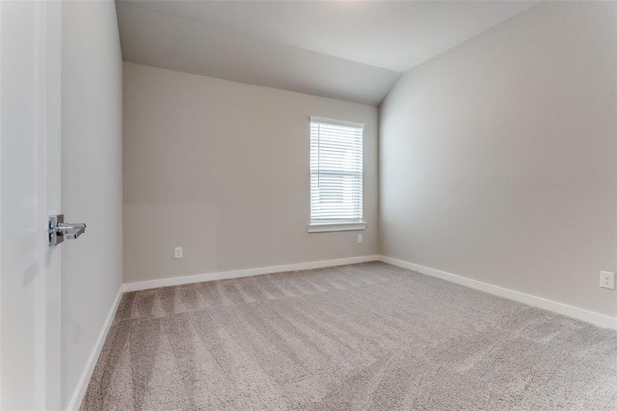 Carpeted empty room with vaulted ceiling