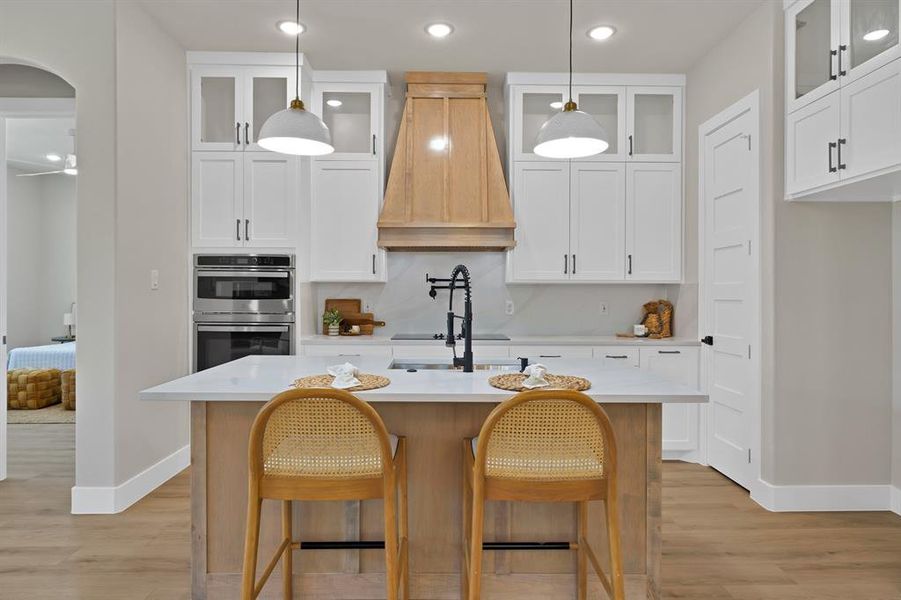 Kitchen featuring premium range hood, stainless steel double oven, baseboards, light wood-type flooring, and recessed lighting Kitchen featuring premium range hood, stainless steel double oven, baseboards, light wood-type flooring, and recessed lighting
