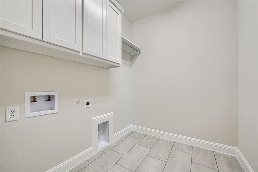 Laundry room with hookup for an electric dryer, light tile patterned floors, hookup for a washing machine, cabinets, and hookup for a gas dryer