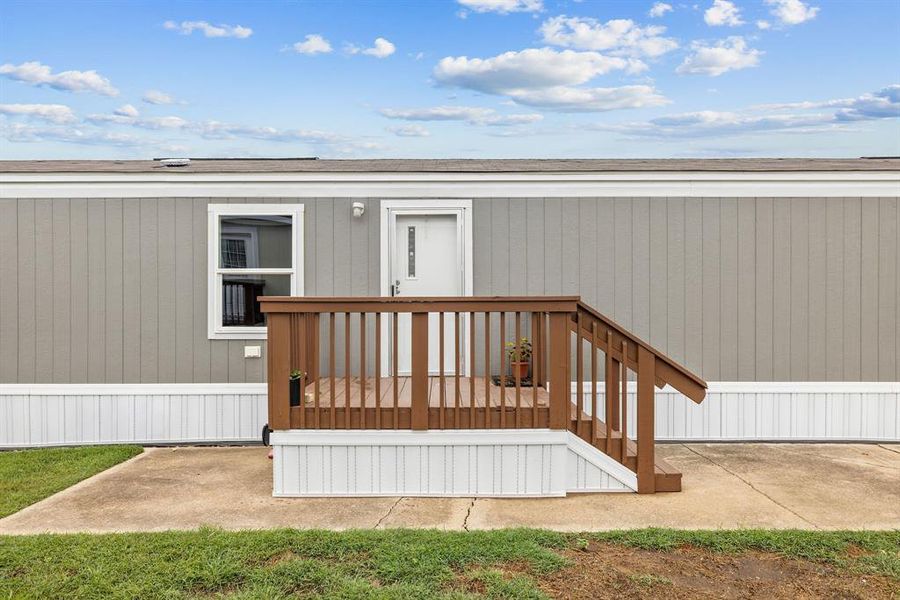 Exterior featuring gray vertical siding, white trim, and a wood deck with railings Exterior featuring gray vertical siding, white trim, and a wood deck with railings