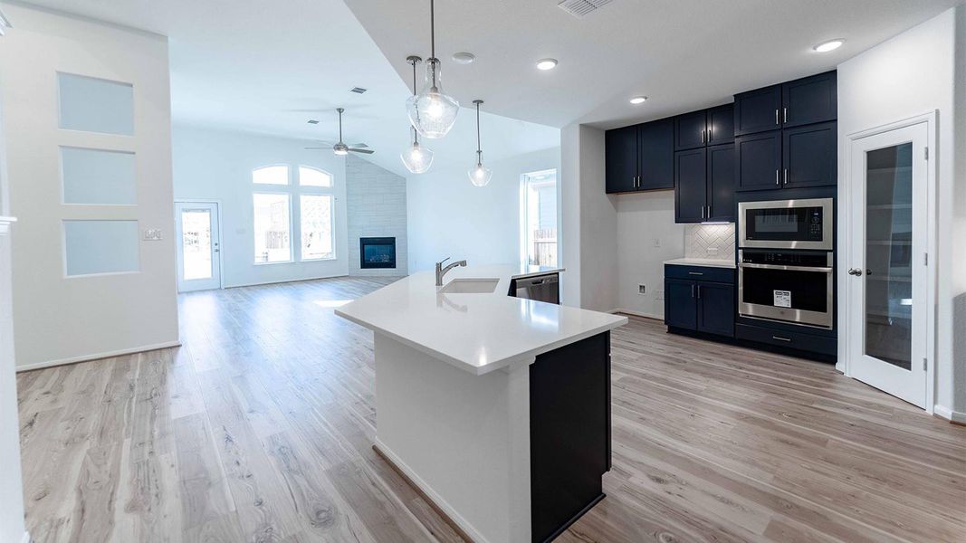 Kitchen with a fireplace, stainless steel appliances, open floor plan, lofted ceiling, and a center island with sink
