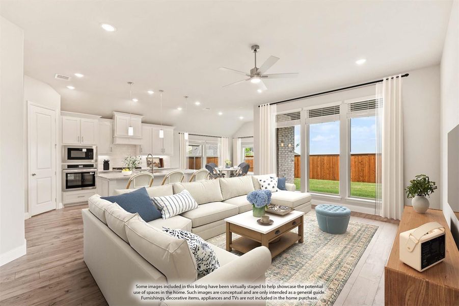Open-concept living room with sectional sofa, ceiling fan, and kitchen visible in background with hardwood floors Open-concept living room with sectional sofa, ceiling fan, and kitchen visible in background with hardwood floors