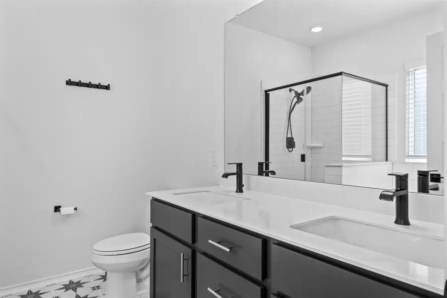 Full bath featuring a shower stall and double vanity
