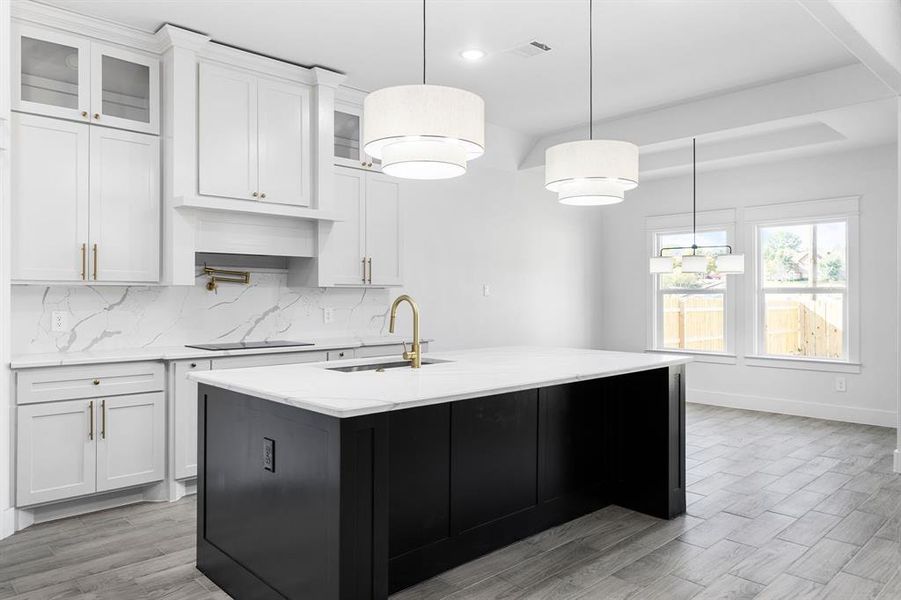 Kitchen with black electric stovetop, white cabinetry, and sink