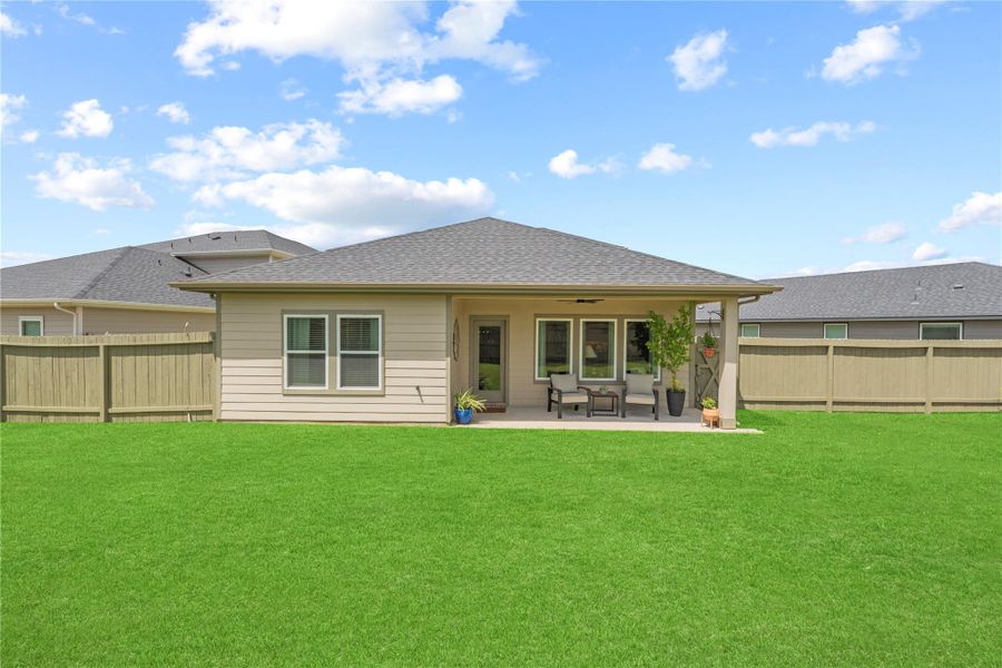 Rear elevation with a covered patio and board fencing, viewed from the back of the yard.