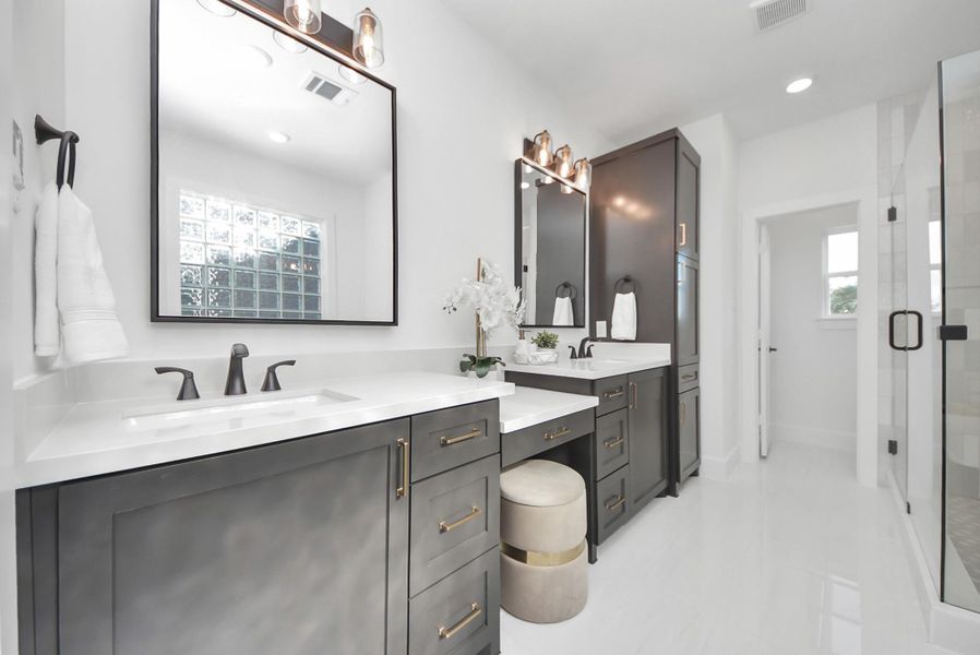 The modern bathroom impresses with dual vanities in dark cabinetry, white countertops, and stylish black fixtures. Elegant mirrors with overhead lighting, a large glass-enclosed shower, and abundant natural light create a bright, airy, and sophisticated space. The modern bathroom impresses with dual vanities in dark cabinetry, white countertops, and stylish black fixtures. Elegant mirrors with overhead lighting, a large glass-enclosed shower, and abundant natural light create a bright, airy, and sophisticated space.