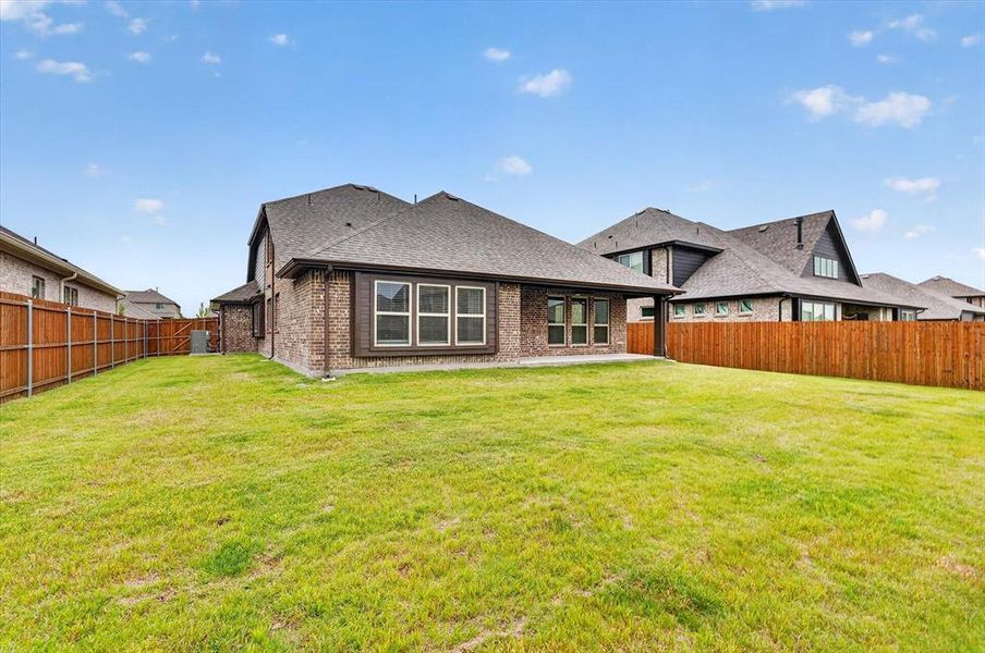 Spacious backyard featuring a manicured lawn, full privacy fencing, and a covered patio Spacious backyard featuring a manicured lawn, full privacy fencing, and a covered patio