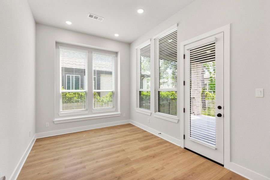 Sunlit dinning room with wide windows, recessed lighting, and glass door to the patio.