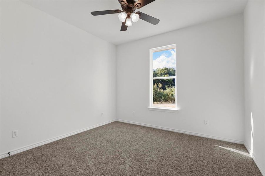 Carpeted spare room featuring ceiling fan