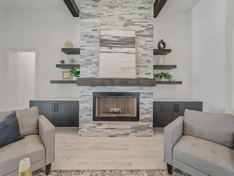 Living room featuring light wood-type flooring, beam ceiling, and a fireplace
