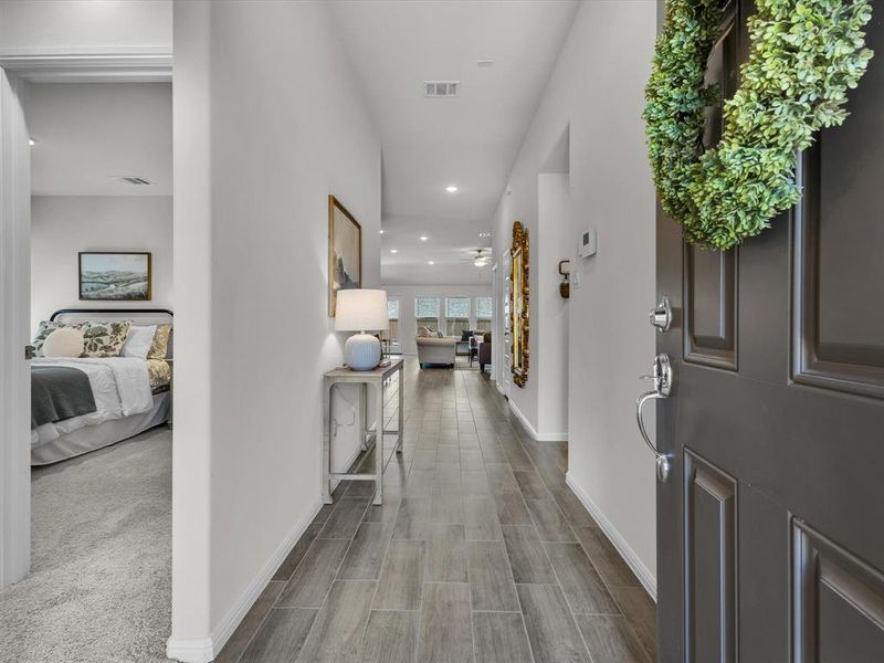 A light filled entry with sweeping wood-look tile floors carry you through the threshold of your dream home!