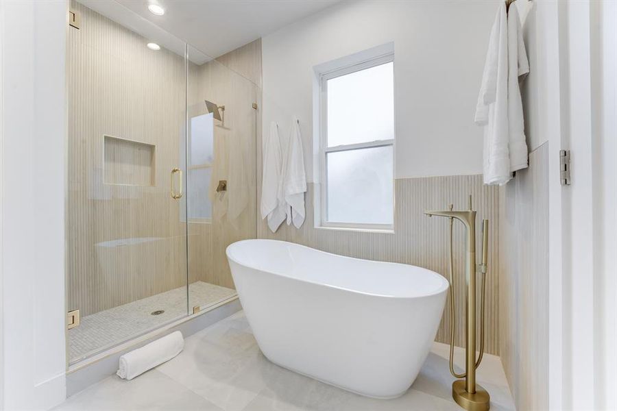 The beautiful porcelain garden tub and frameless tiled shower with the large accented window offers a spa-like experience in the home.