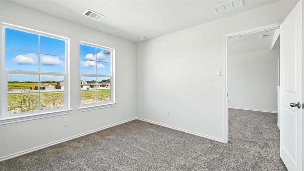 Bright room featuring two large windows with white trim, soft gray carpet, white walls, recessed lighting, and a white interior door with black hardware