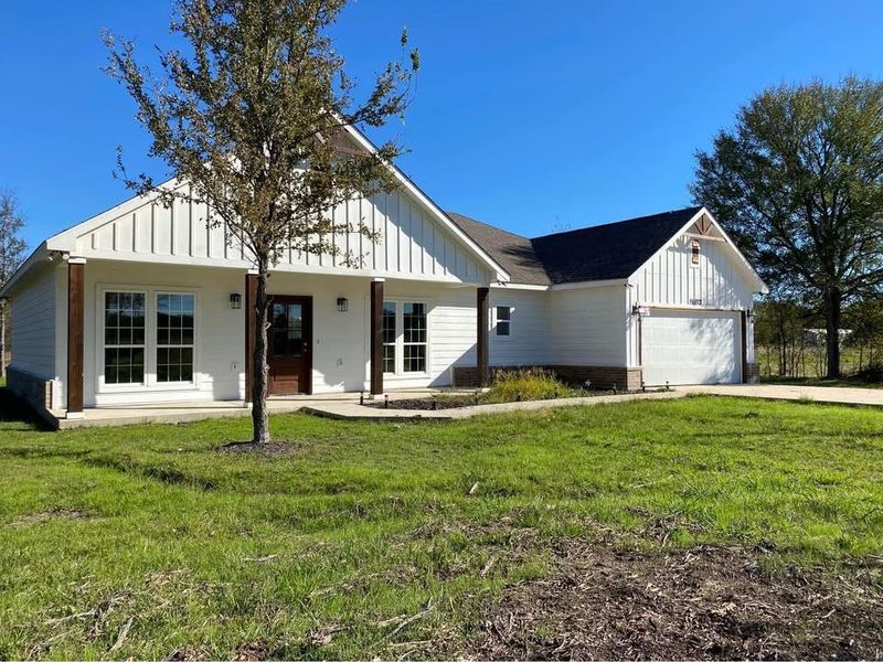 View of front facade with covered porch, a garage, and a front lawn