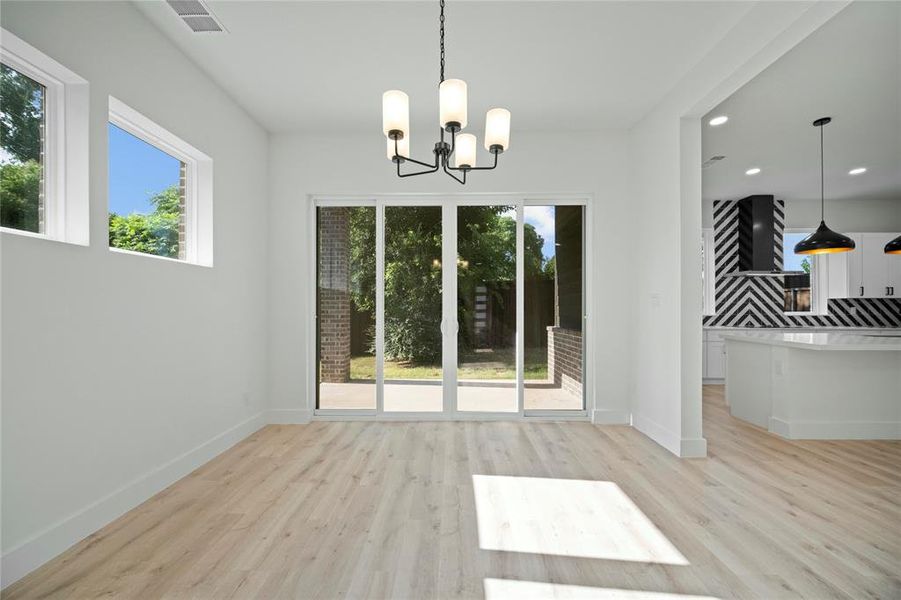 Unfurnished dining area featuring healthy amount of natural light, light wood-style floors, a chandelier, and recessed lighting