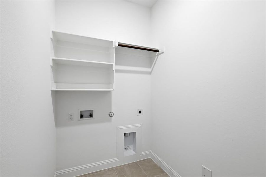 Laundry area featuring hookup for an electric dryer, washer hookup, light tile patterned floors, and hookup for a gas dryer